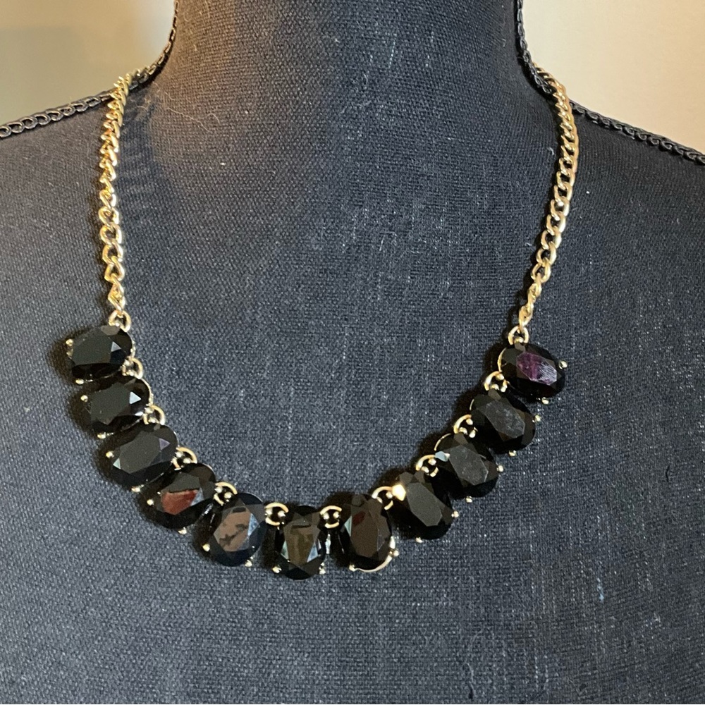 Black statement necklace with gold tone chain.